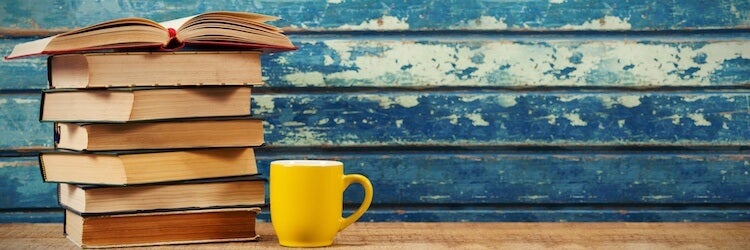 How to sell books on Amazon: stack of books and a yellow mug in front of a wall