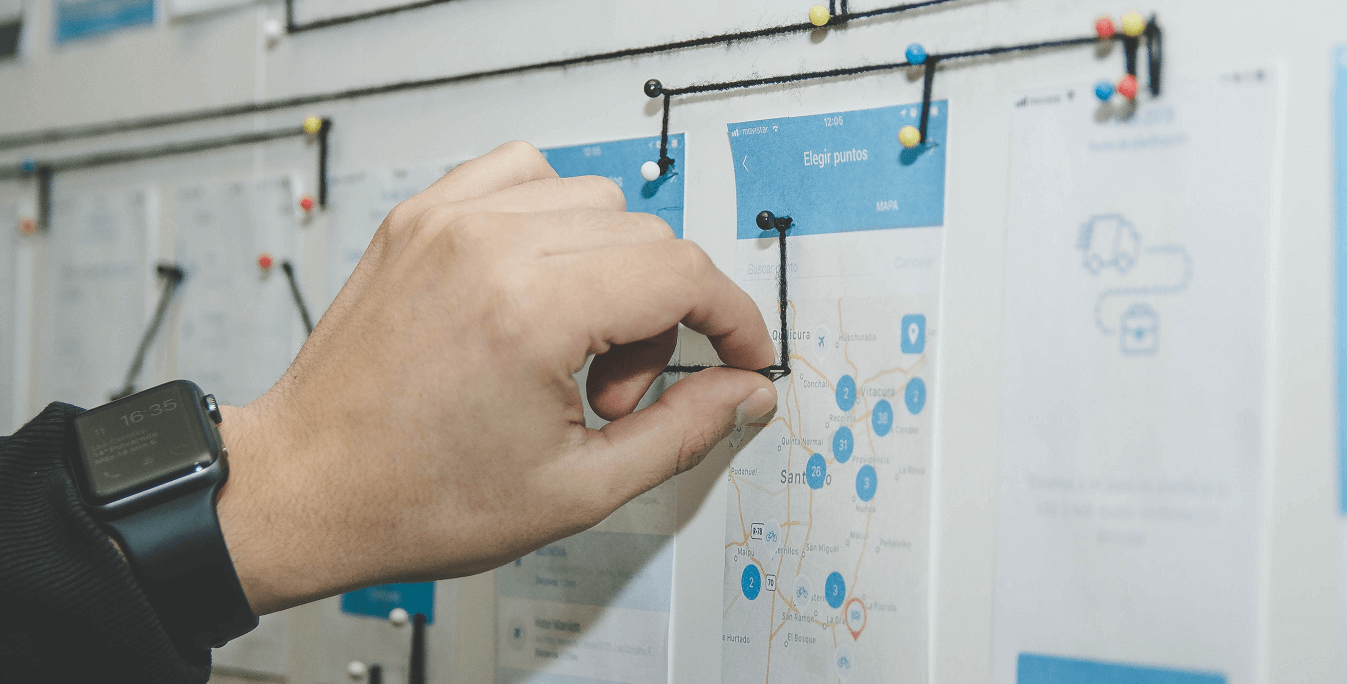 hand pushing in pin on white and blue board