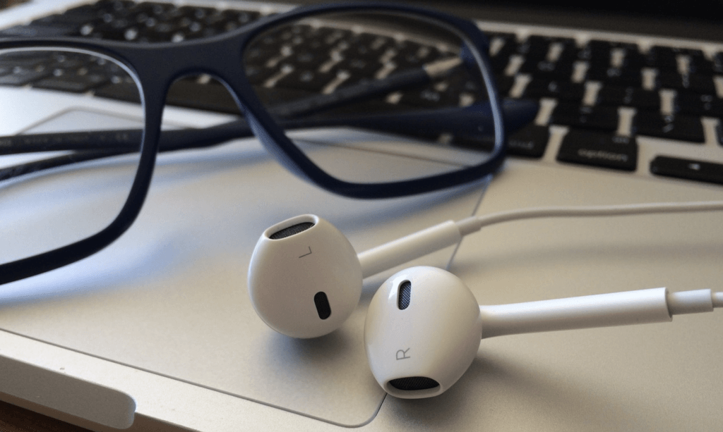 ecommerce podcasts: glasses and earphones on a laptop