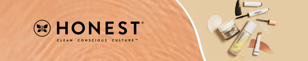 A banner image for the Honest Beauty brand. The image shows a cool peach sand background, with a tan block on the right side that shows a series of beauty products lying on a table. Over the peach background is the Honest logo that reads "Honest. Clean. Conscious. Culture."