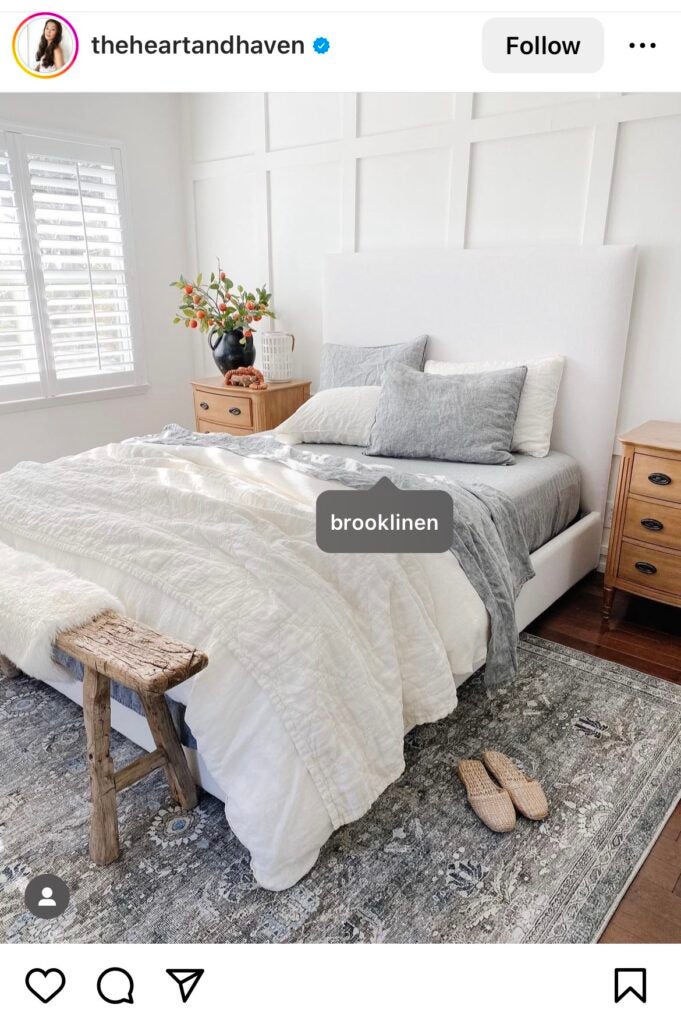 An image of an Instagram post displaying an example of influencer marketing. The post shows a bed decorated with gray sheets and a white comforter. The image shows that the brand Brooklinen is tagged in the post.